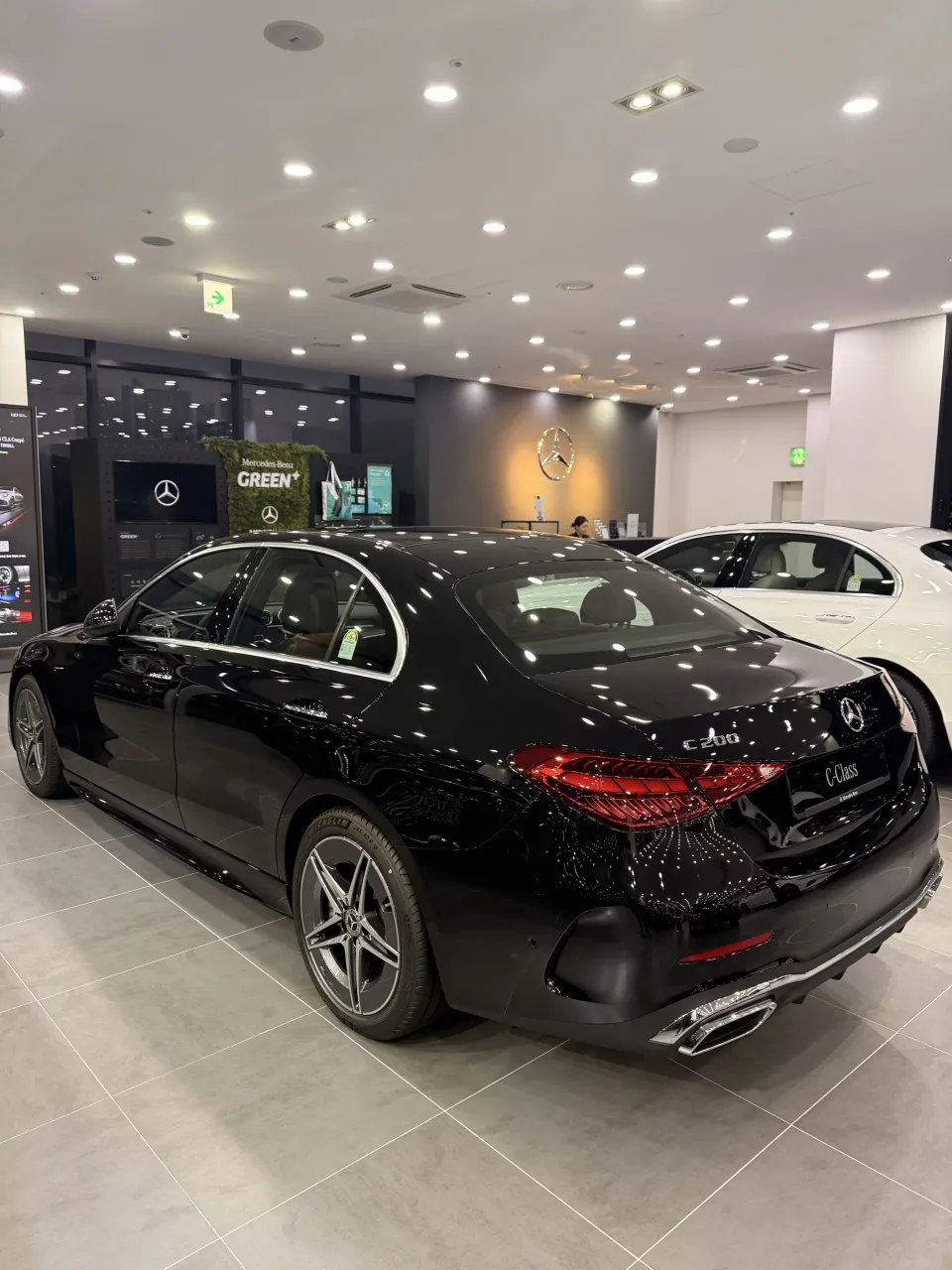 전시장에서 비스듬히 촬영한 검은색 벤츠 C-Class 세단 측후면
