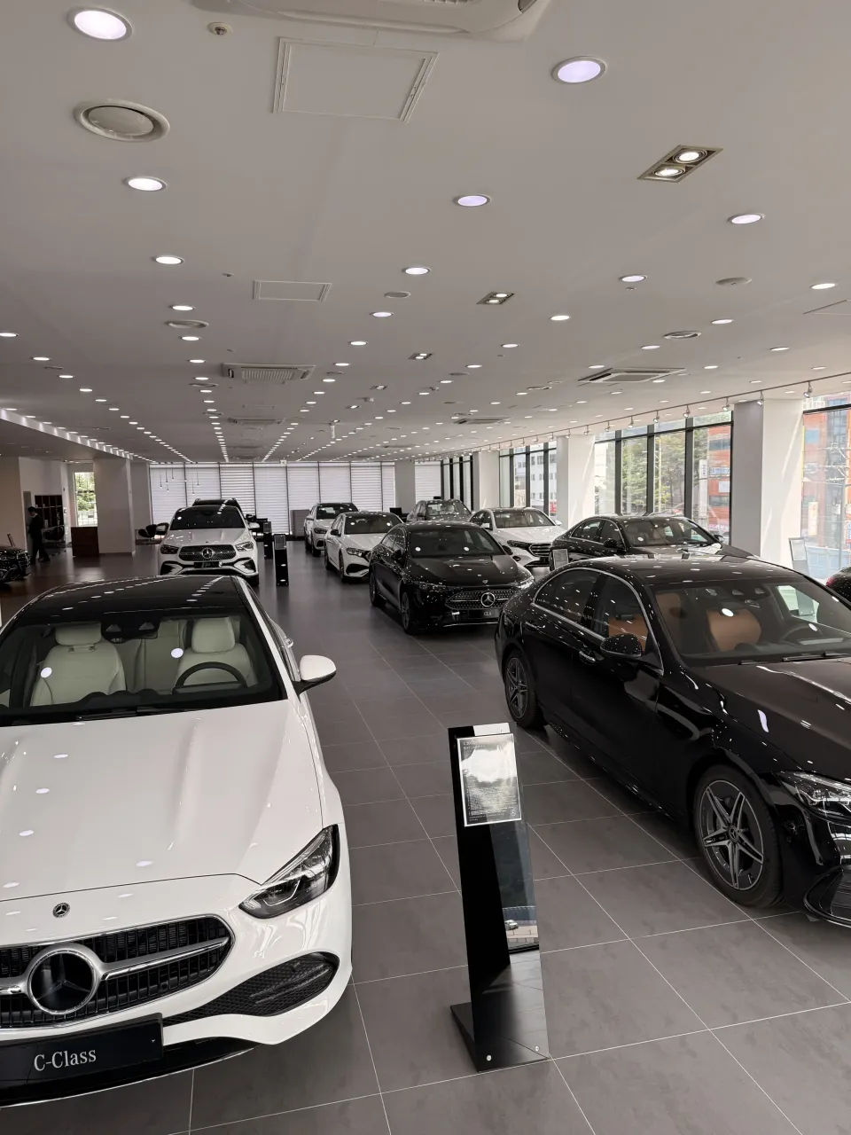 의정부 전시장 안에 전시된 흰색 메르세데스-벤츠 C-Class 세단과 C-Class 안내 스탠드